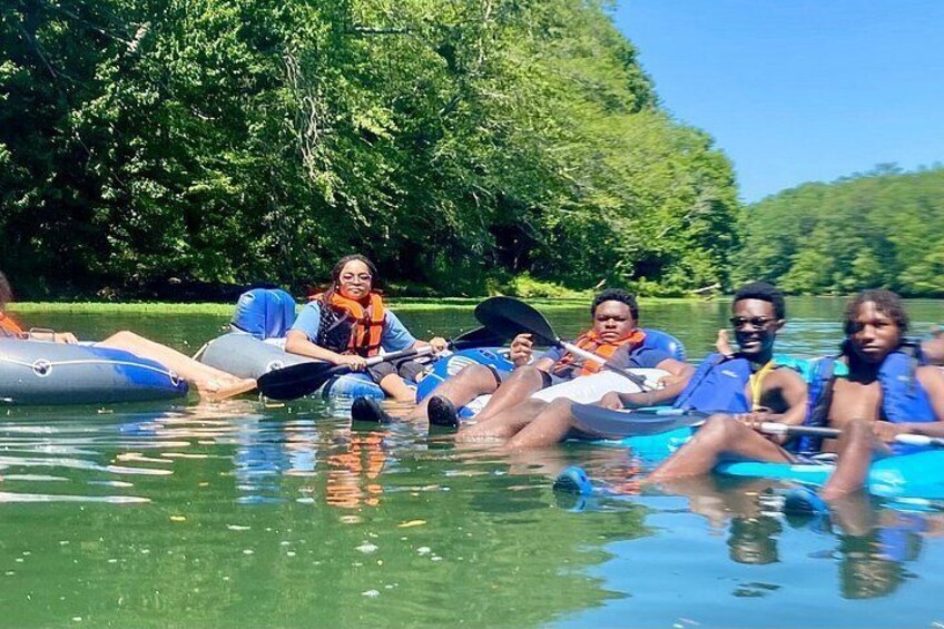 People in inflatable rafts on a river surrounded by greenery. 3