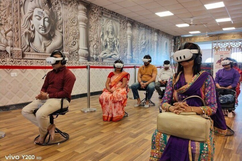 People using virtual reality headsets in a room with a mural of deities. 3