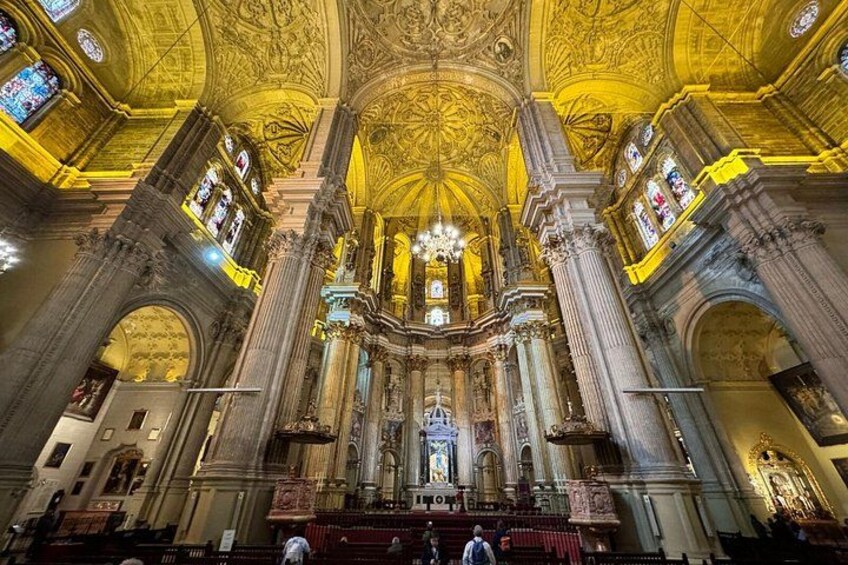 An ornate church interior with a high ceiling, stained glass windows, and a central altar. 1