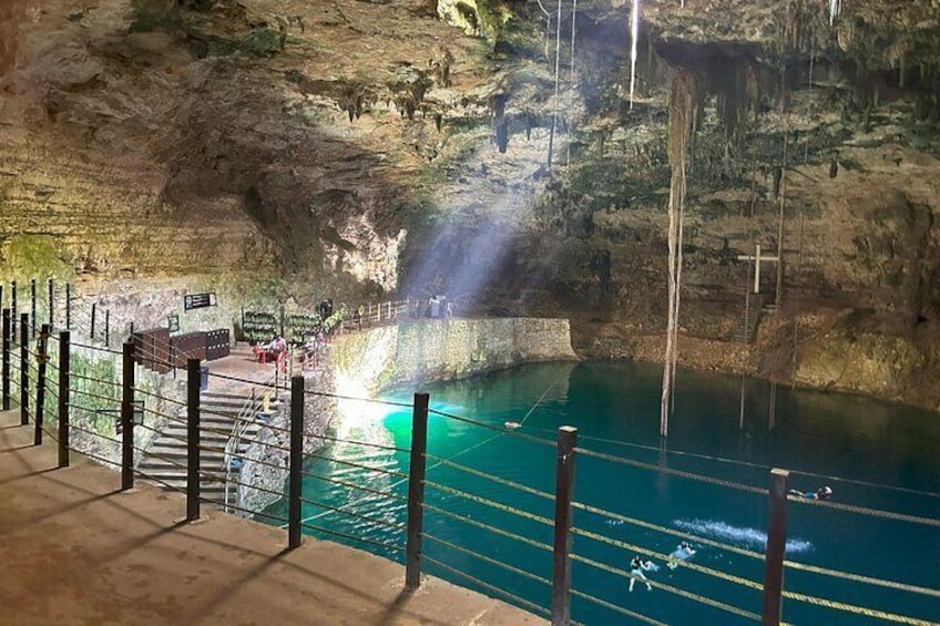 A cave with a pool of water, a staircase, and a railing. 3