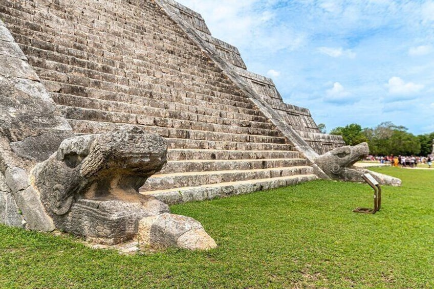 A large stone pyramid with steps and a carved stone head at the base. 1