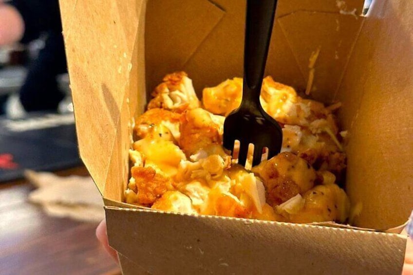 A cardboard container with a fork inside, containing a food item. 4