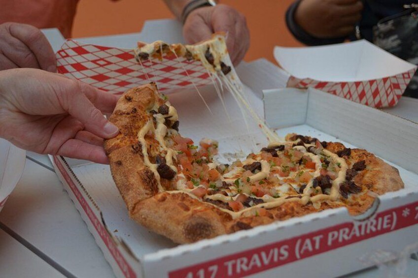 A pizza with toppings being lifted from a box. 2