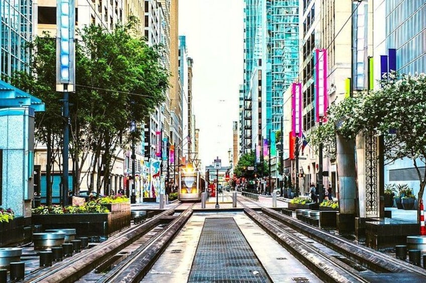 A city street with a tram, tall buildings, and colorful banners. 3