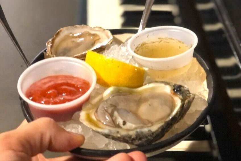 A tray of oysters with lemon wedges and two dipping sauces. 2
