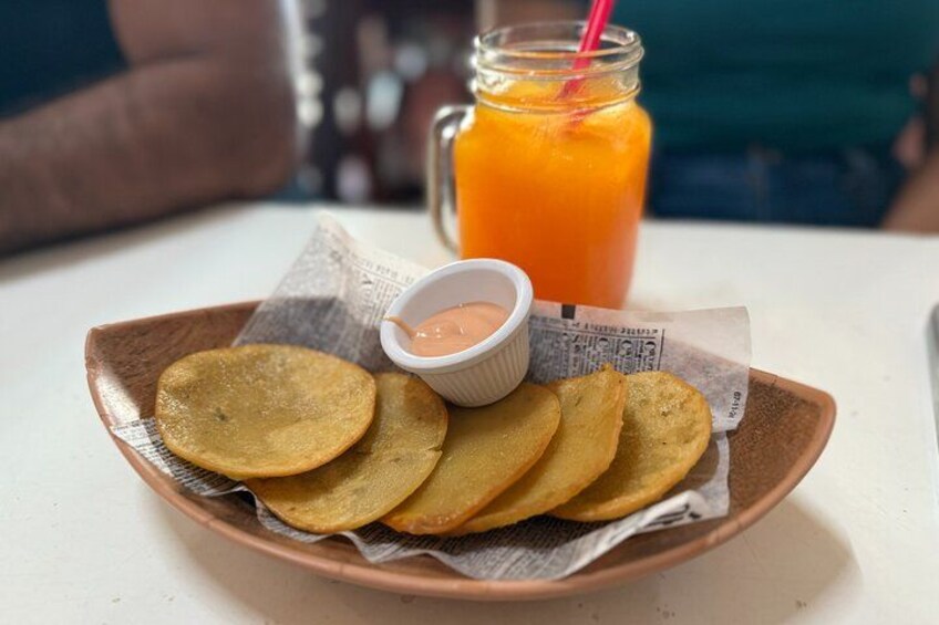 Un plato de plátanos fritos con salsa para mojar y un vaso de jugo de naranja. 5