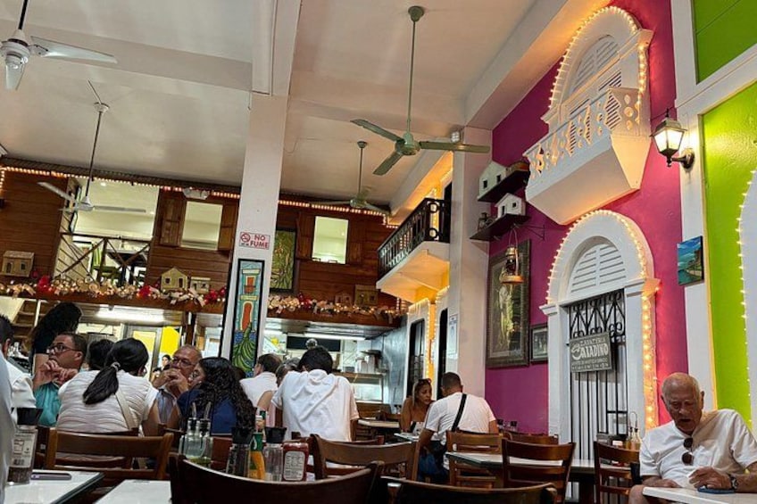 A bustling restaurant interior with wooden furniture, a staircase, and decorative lighting. 4