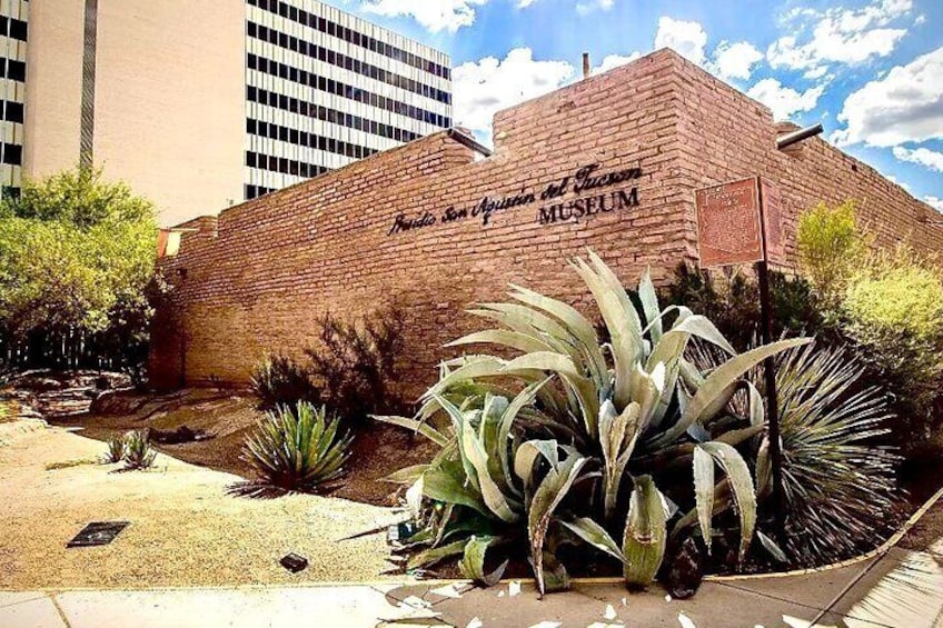 The exterior of the Florida State Museum with a brick facade and large agave plants in the foreground. 3