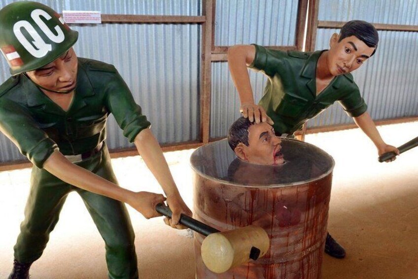 A person in a green uniform with a hat marked 'QC' using a hammer on a barrel. 4