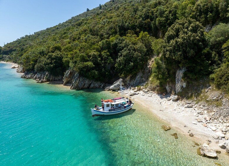 A boat named 'MARINE ADVENT' anchored near a turquoise beach with rocky cliffs and dense greenery. 1