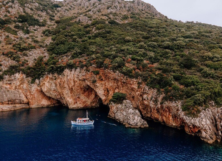 A boat navigating through a natural rock arch in a coastal area. 5