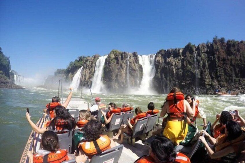 A group of people on a boat near a waterfall. 1