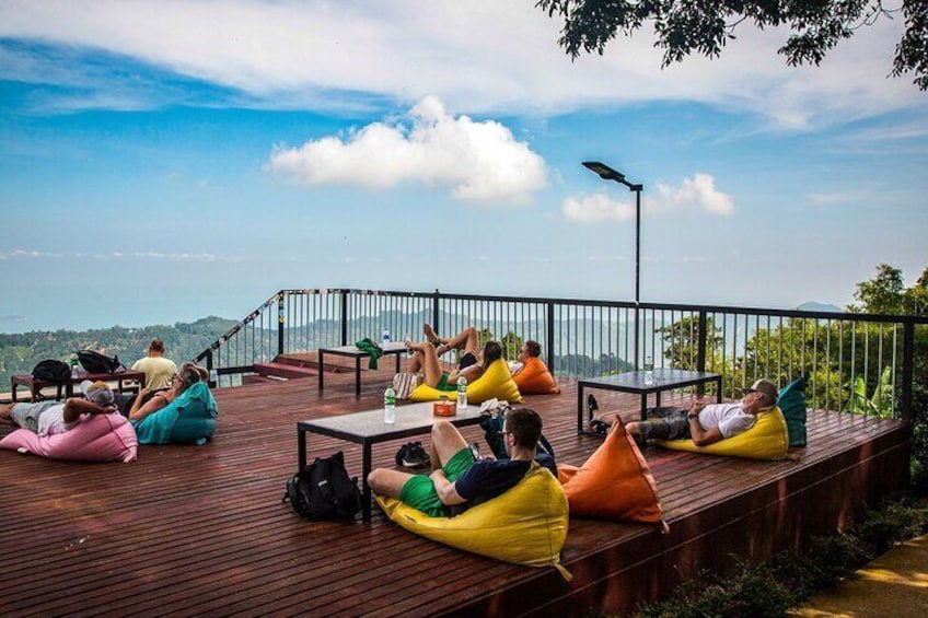 People relaxing on a wooden deck with bean bags, overlooking a scenic landscape. 3