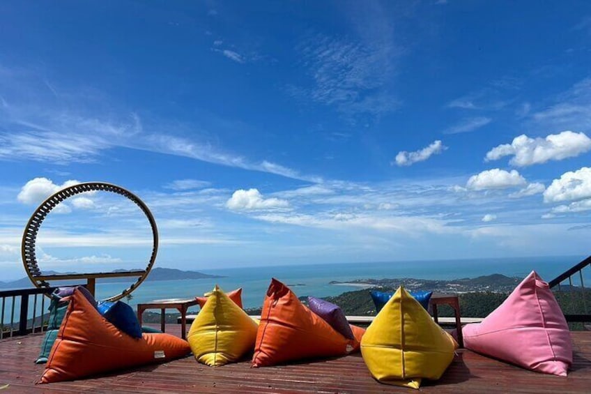 A deck with colorful bean bags and a ring stool overlooking a coastal landscape. 5