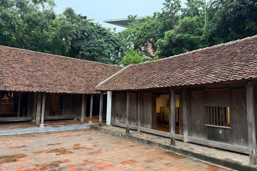 A courtyard with tiled roofs and wooden structures, surrounded by trees. 5