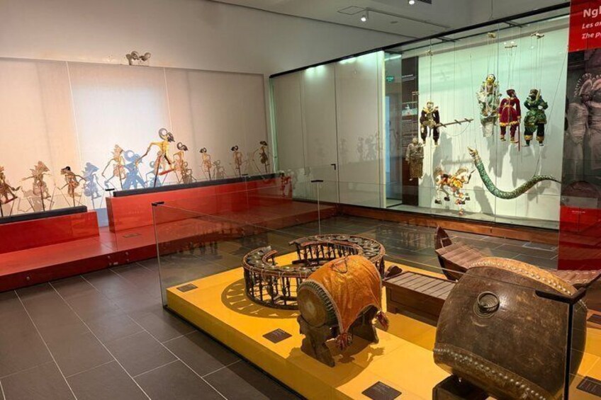 A museum exhibit with various cultural artifacts, including a large wooden wheel and a bronze sculpture. 3