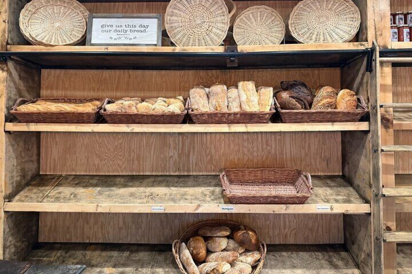A bakery shelf with various breads and baskets. 5