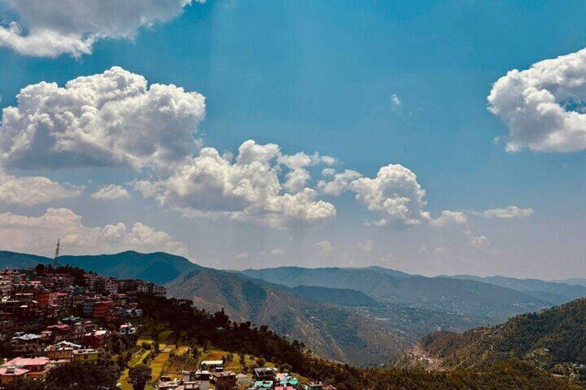 A mountainous landscape with a village, clear sky, and scattered clouds. 4
