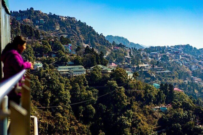 A mountainous landscape with scattered houses and dense greenery. 1