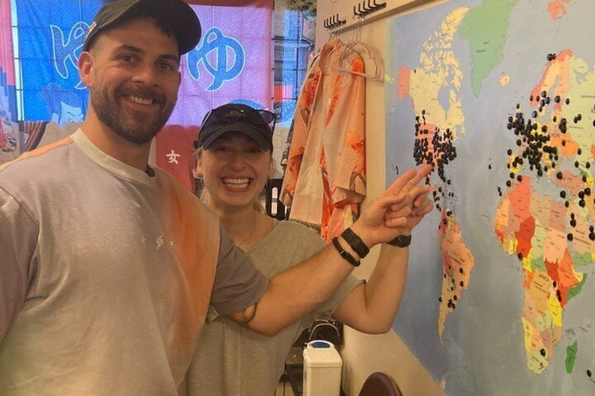 Two people standing in front of a world map with pins. 5