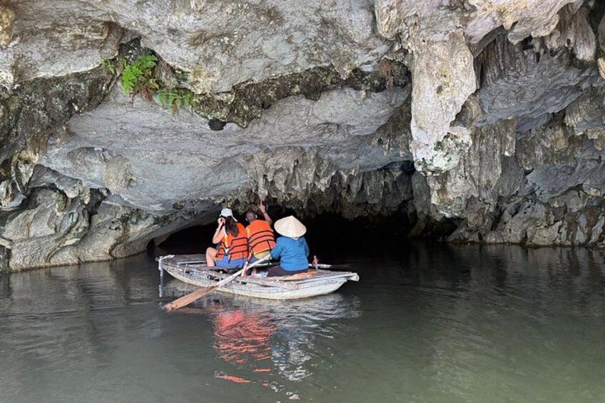 A group of people in a small boat navigating through a cave entrance. 4