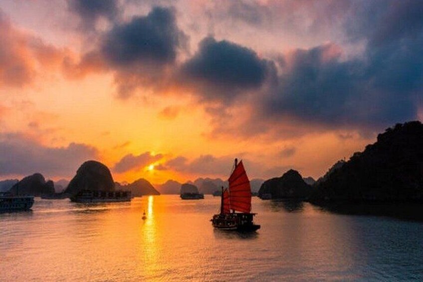 A sunset over a body of water with a sailboat and several boats. 5
