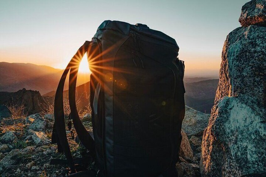 A backpack on rocky terrain with a sunrise in the background. 5