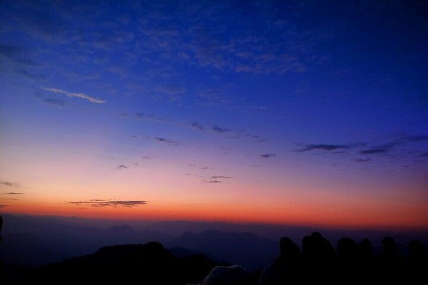 A sunset over a mountainous landscape with silhouettes of trees. 3
