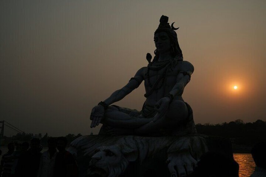 A statue of a deity in a meditative pose with a sunset in the background. 2