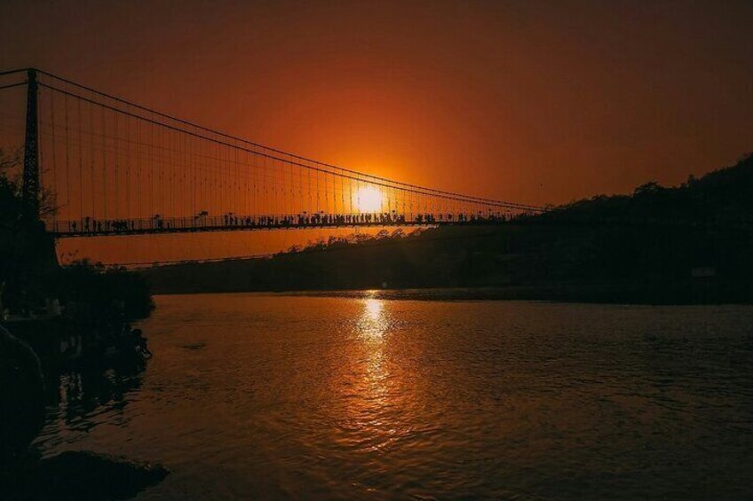 A bridge at sunset with the sun setting behind it, reflecting on the water. 4