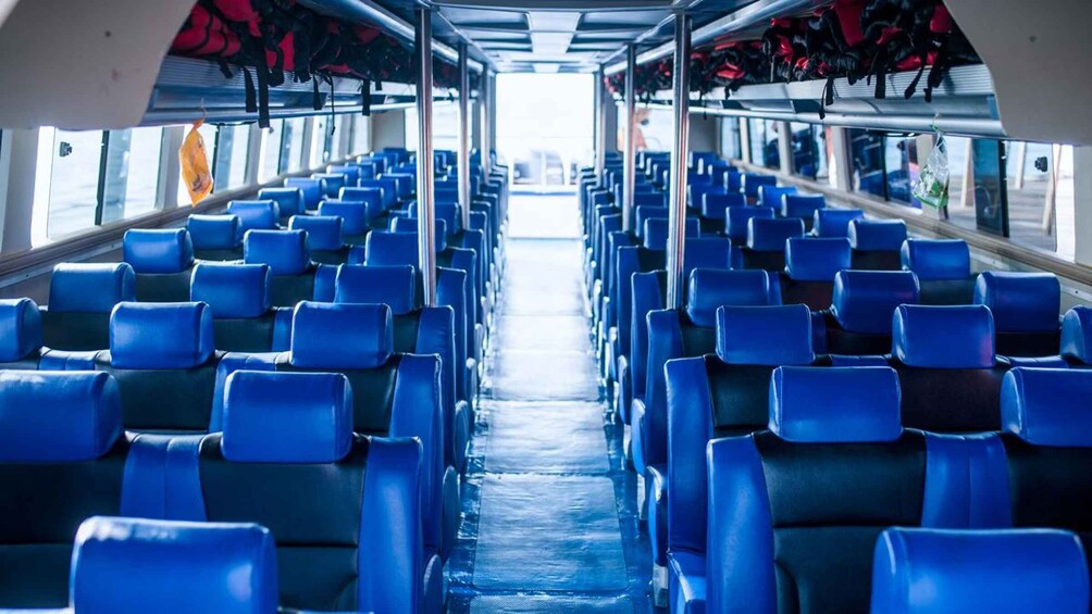 A bus interior with rows of blue seats and overhead luggage racks. 3
