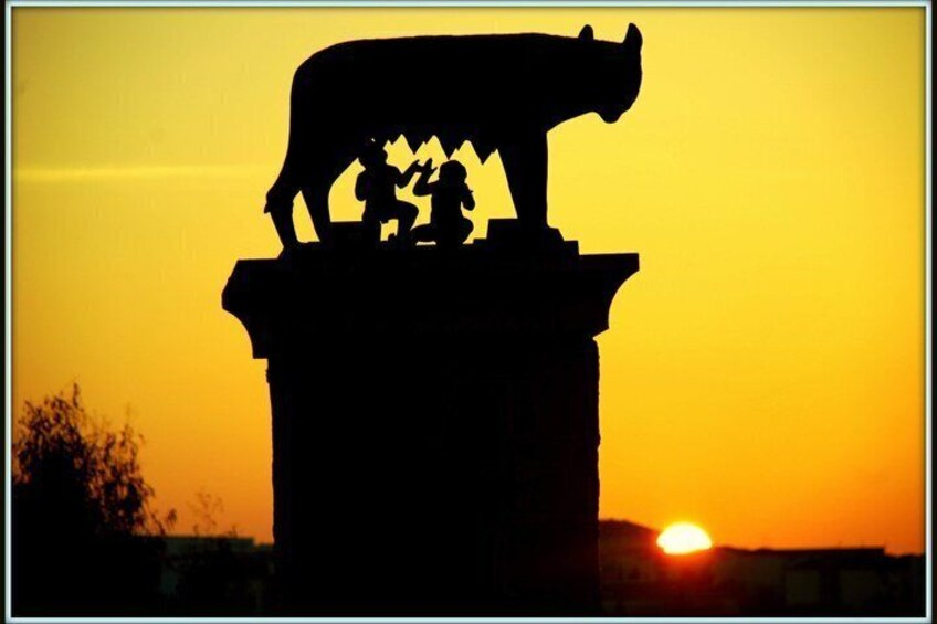 A silhouette of a bull statue with two children on a pedestal against a sunset. 1