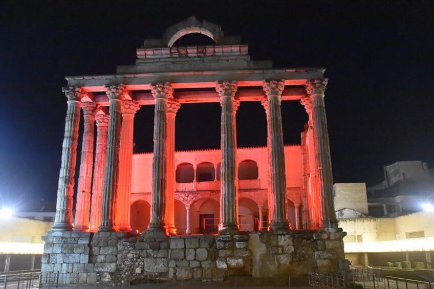 Un edificio clásico con columnas y arcos, iluminado por la noche. 3