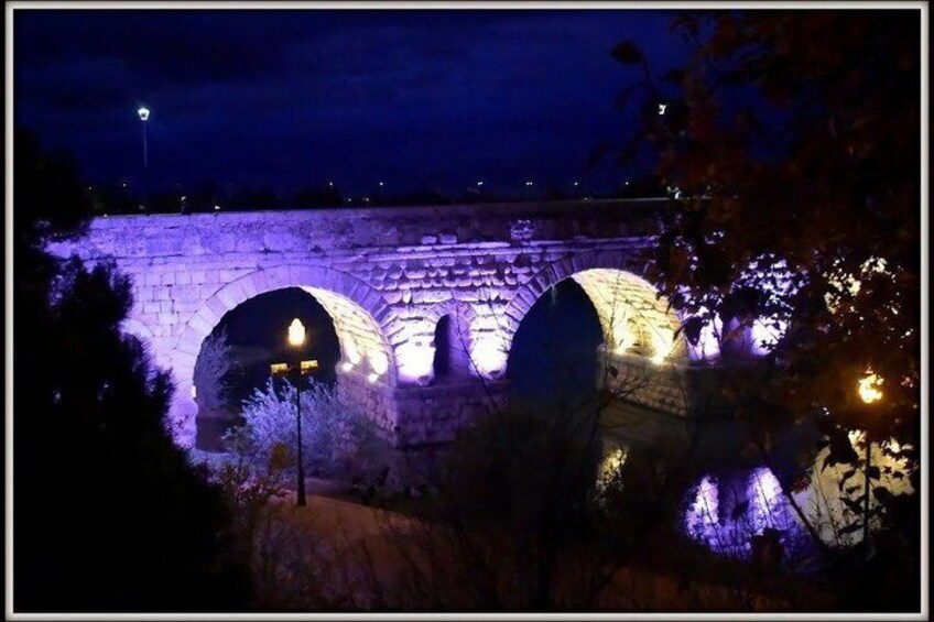 A stone bridge with illuminated arches at night. 2