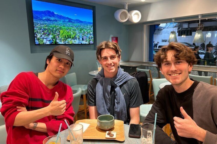 Three people sitting at a table with a laptop, a bowl, and a glass. 1