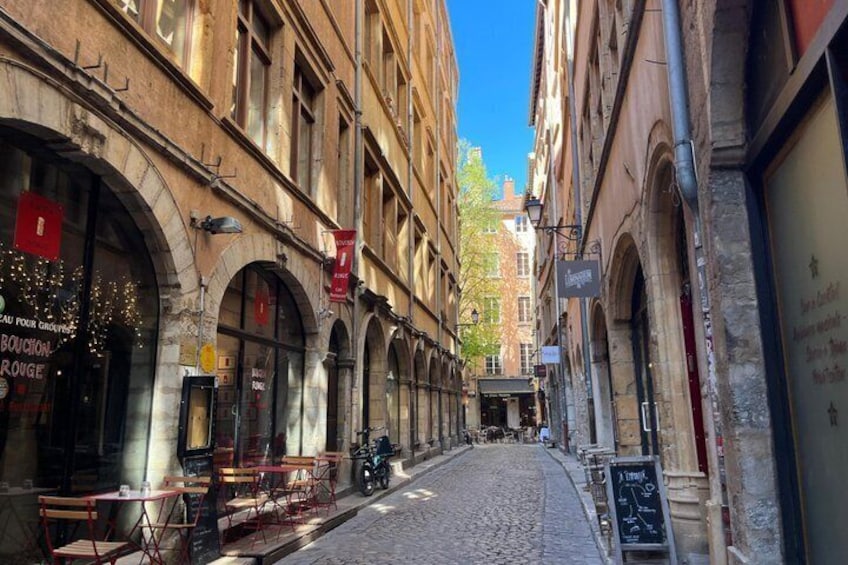 A cobblestone street lined with historic buildings, outdoor seating at cafes, and a clear blue sky. 5