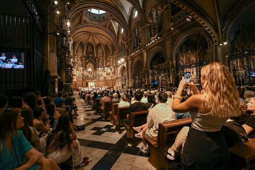 A cathedral interior with pews, a large organ, and a person taking a photo. 5