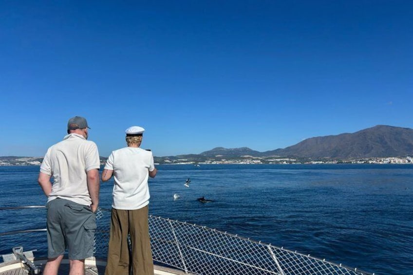 Two people on a boat, a mountainous landscape, and a clear blue sky. 3