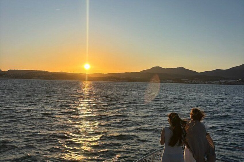 Een zonsondergang boven een wateroppervlak, met bergen op de achtergrond. 3