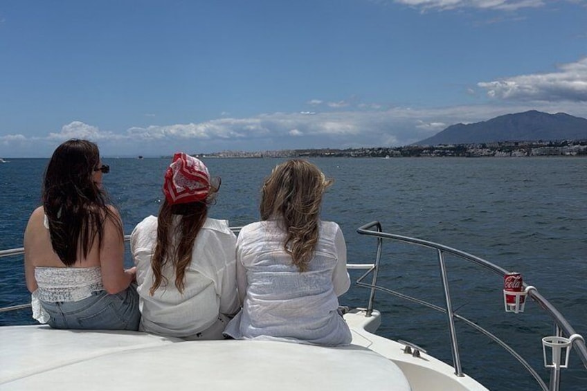 Three people on a boat, looking at a distant shoreline with mountains. 1