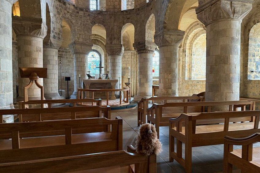 An interior of a church with wooden pews, stone columns, and stained glass windows. 4