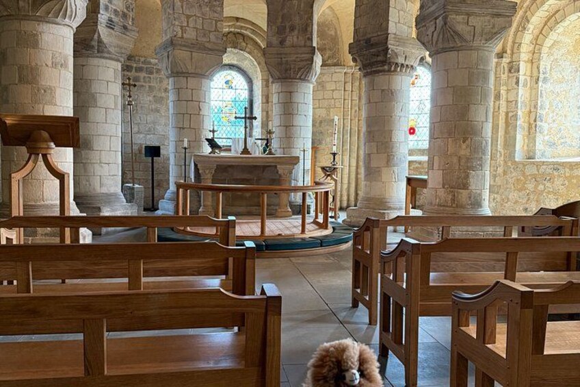 A church interior with wooden pews, stone columns, and a stained glass window. 3