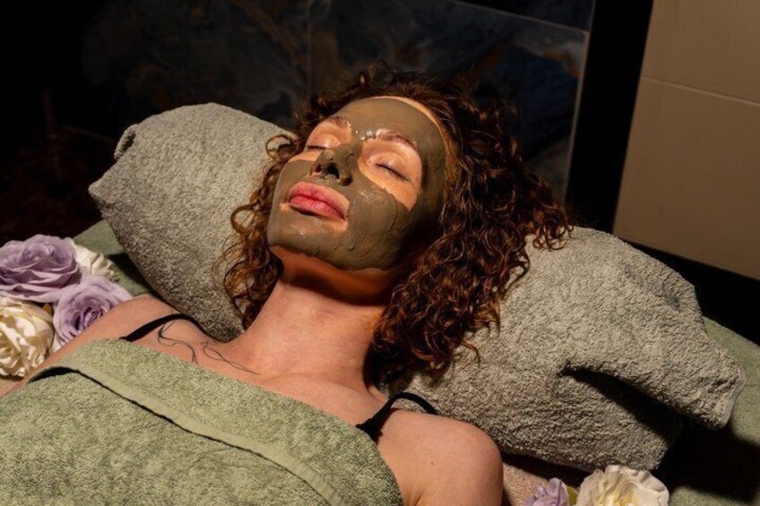 A person lying down with a towel over their head, surrounded by flowers. 4