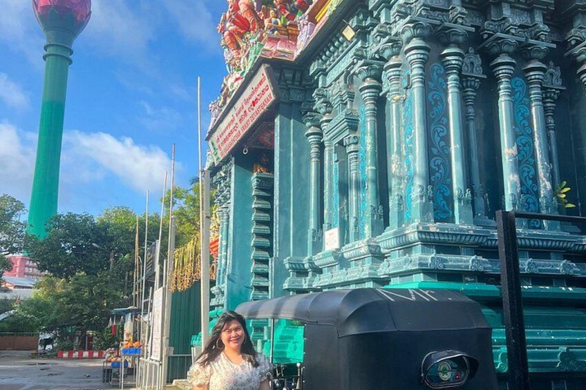 A woman standing in front of a temple with intricate carvings and a tall green pillar. 2