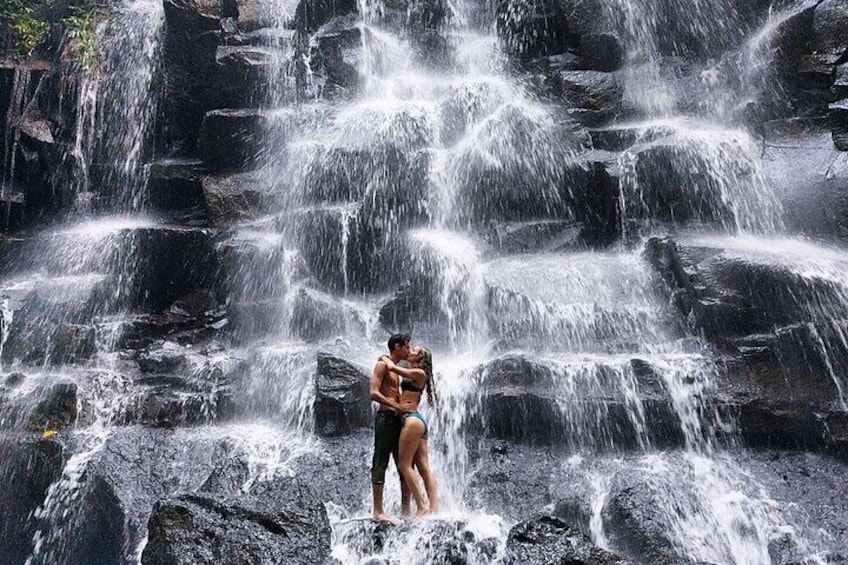 A waterfall with a couple embracing in the foreground. 3