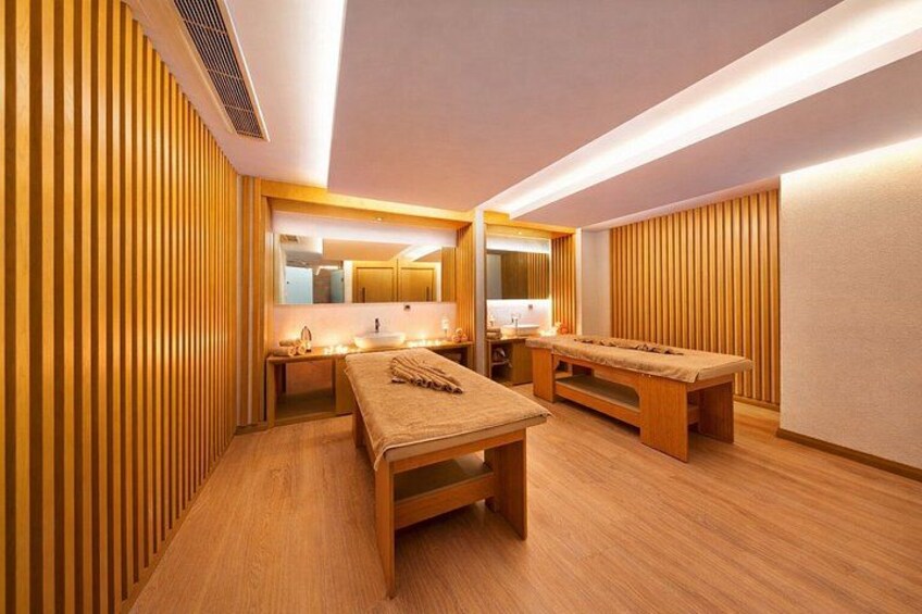 A modern spa room with wooden paneling, a massage table, and a small seating area. 5