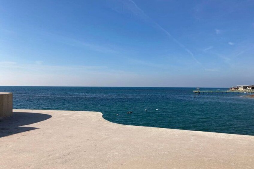 A coastal scene with a sandy beach, calm sea, and a distant pier. 4