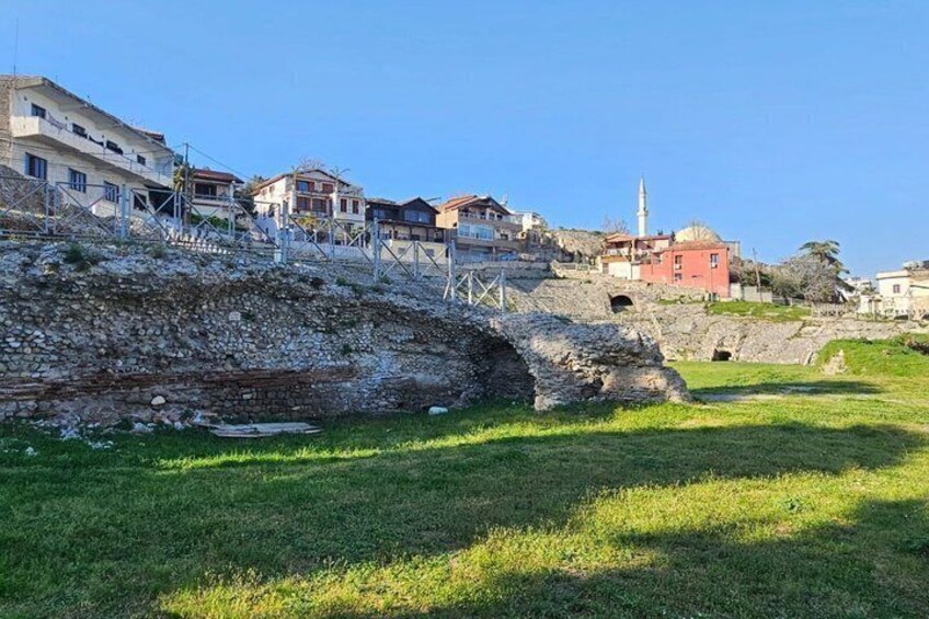A coastal town with stone ruins, modern buildings, and a mosque. 2