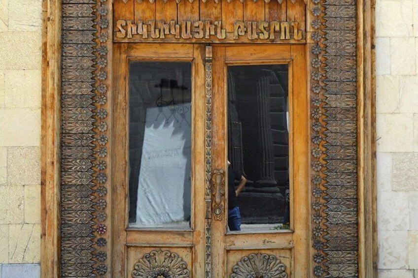 A wooden door with intricate carvings and a sign above it. 3