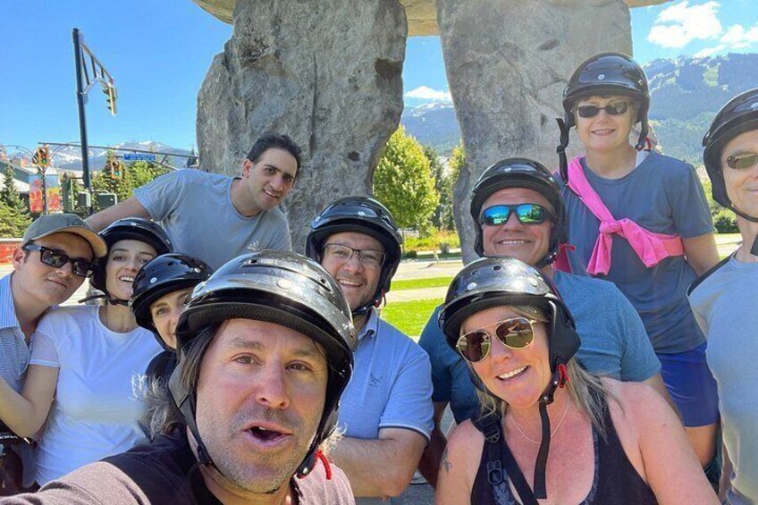 A group of people wearing helmets, standing in front of a large rock formation. 3